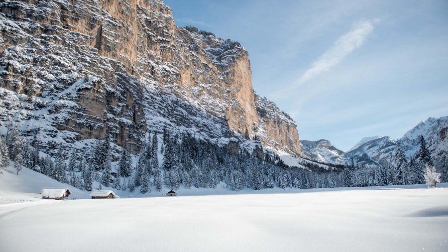 Winterwandern in den Dolomiten rund um das Excelsior Schneebedeckte Berglandschaft mit Tannen und Hütten unter klarem Himmel