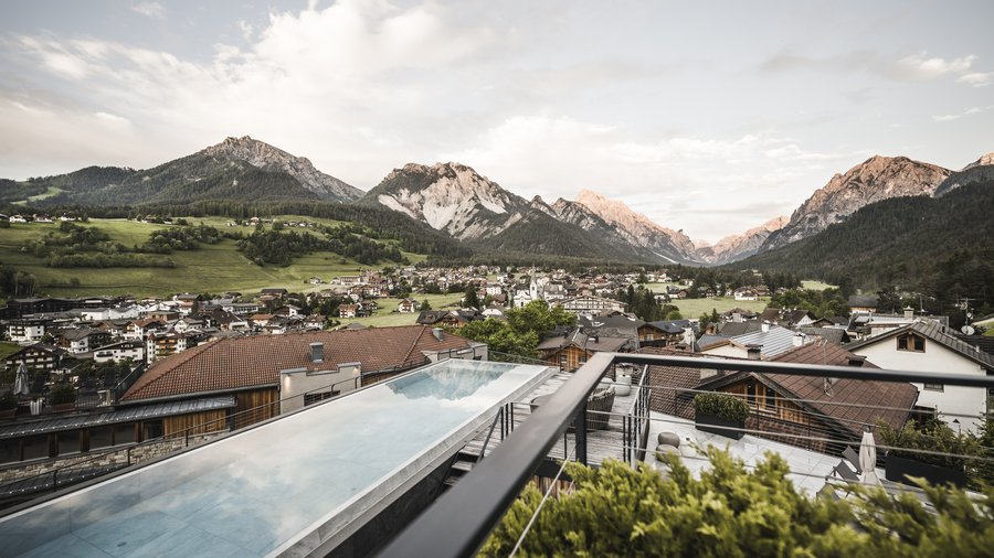 South Tyrol: wellness holiday à la Excelsior Mountain village with pool and mountains in the background at sunset