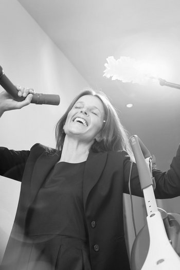 Benvenuti nel vostro hotel al Plan de Corones! Donna canta giocando con aspirapolvere e piumino nel corridoio