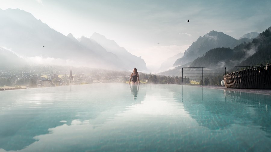 Aktivurlaub: Ihr Hotel mit Fitnessstudio in Südtirol Frau entspannt im Infinity-Pool mit Bergblick und nebliger Landschaft