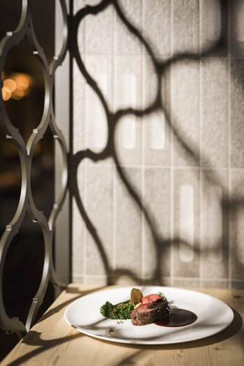 Wellnesshotel in Südtirol: Auf in den Traumurlaub! Gebratenes Fleisch mit Brokkoli und dunkler Sauce auf einem weißen Teller