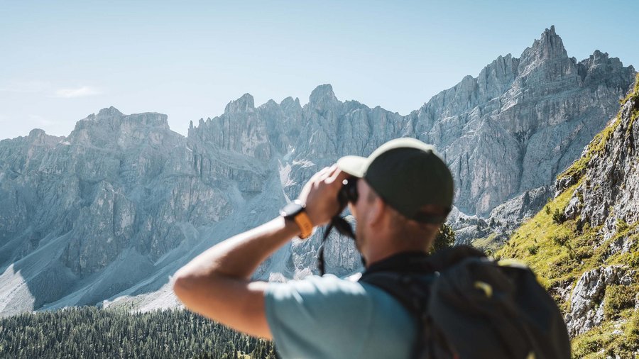 Mountain hotel in the Dolomites/South Tyrol Hiker with binoculars looking at rocky mountain range