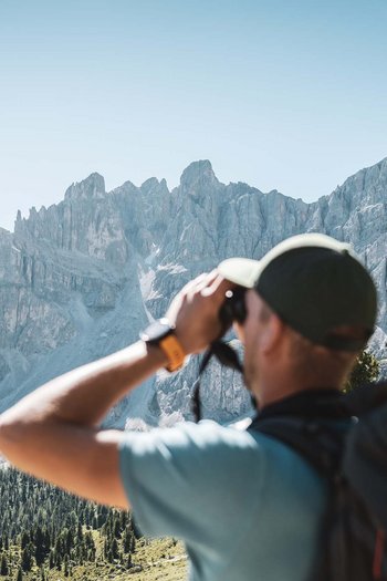 Hotel in South Tyrol with guided hikes Hiker with binoculars looking at rocky mountain range