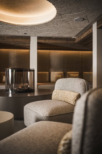 Wellnesshotel in den Dolomiten Gemütlicher Sitzbereich mit Kamin und gedämpfter Beleuchtung