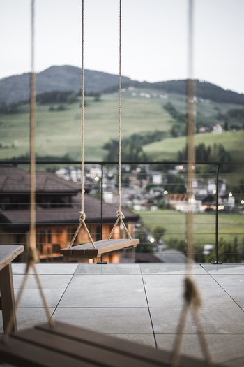 Hotel in the Dolomites for adults only Empty wooden swing on terrace with mountain view in background