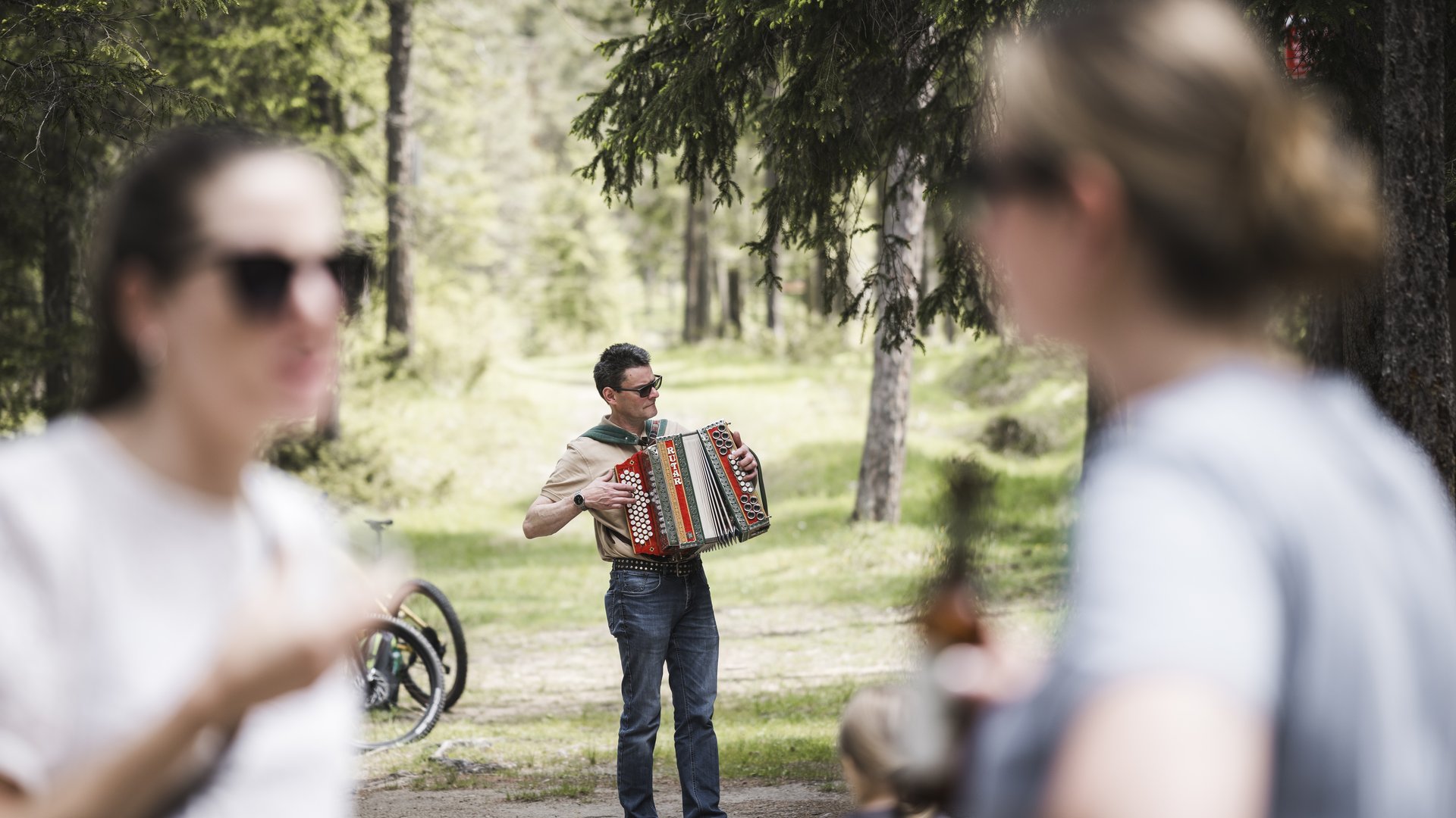 Mountain hotel in the Dolomites/South Tyrol Man playing accordion in forest, people blurred in foreground
