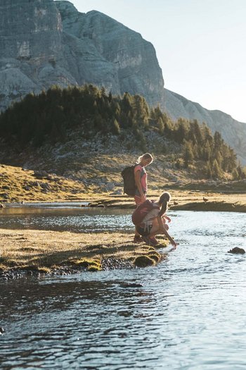 Around the hotel on the slopes in South Tyrol Two hikers by a mountain river at sunset
