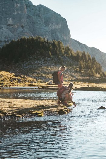 Around the hotel on the slopes in South Tyrol Two hikers by a mountain river at sunset
