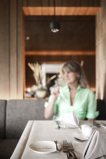 The gourmet hotel in South Tyrol Woman in restaurant with set table and blurred background