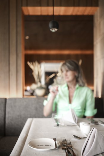 Il vostro hotel gourmet in Alto Adige Donna in ristorante con tavolo apparecchiato e sfondo sfocato