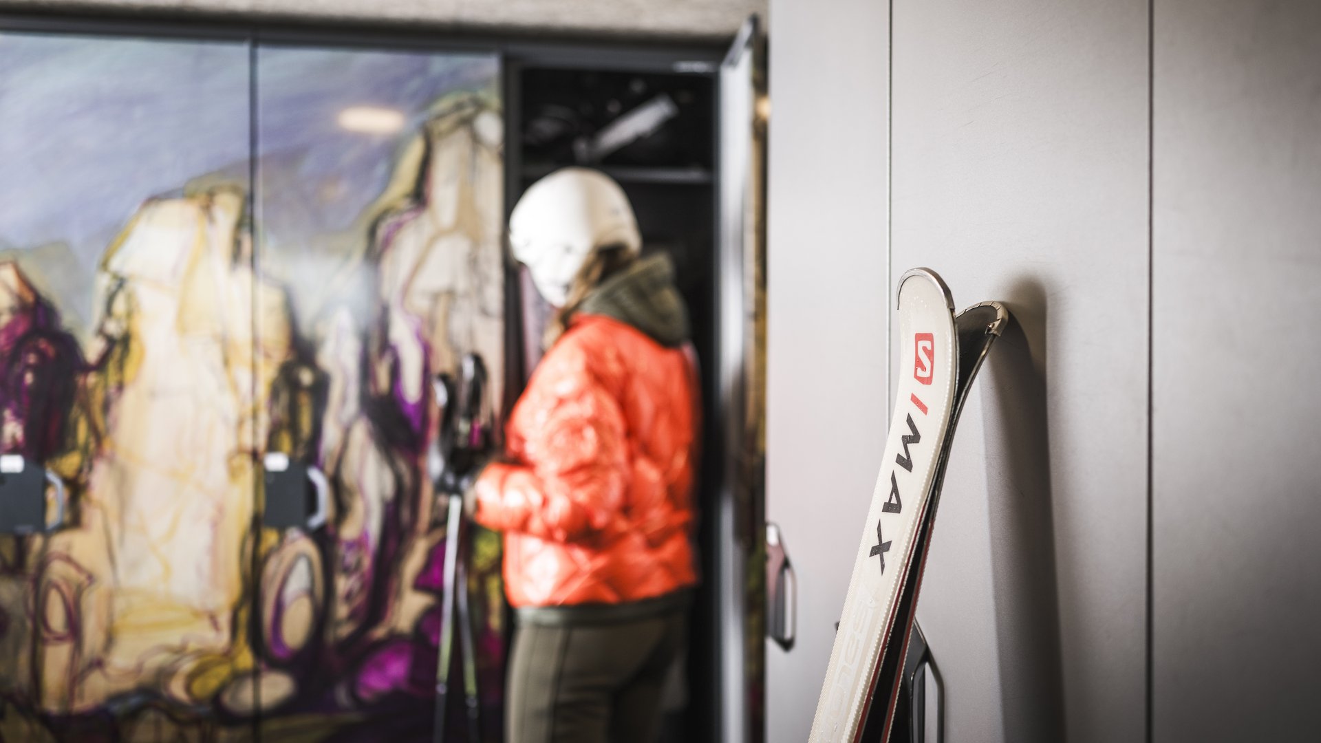 Mountain hotel in the Dolomites/South Tyrol Skis leaning against locker, person in helmet and red jacket in background