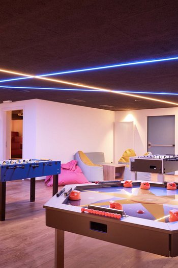 Family-friendly hotel in South Tyrol Modern game room with table tennis, foosball tables, and seating area