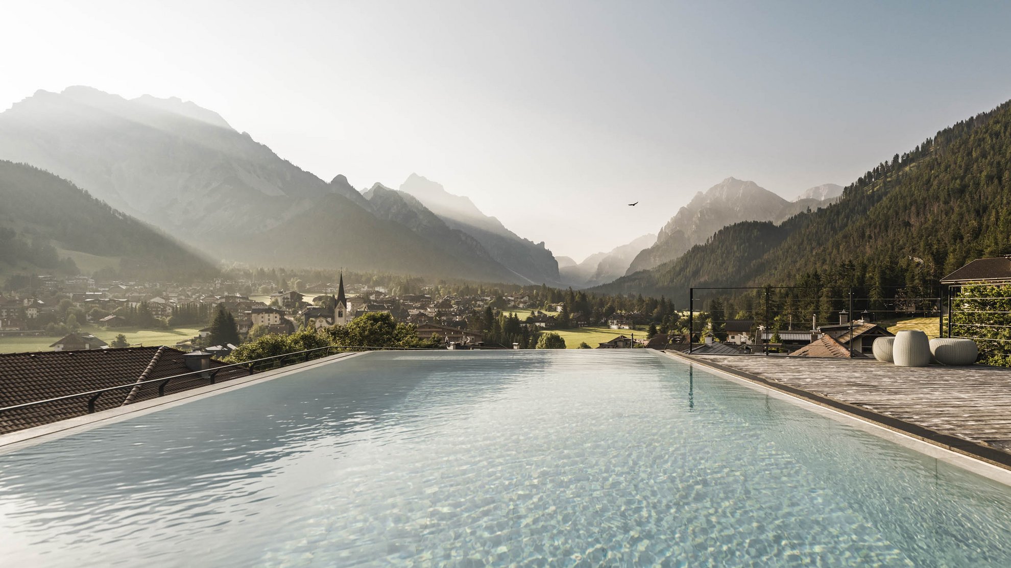 Barrierefreiheit Infinity-Pool mit Blick auf Dorf und Berge im Nebel