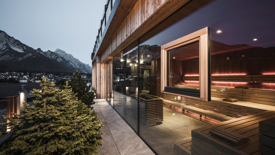 Hotel in den Dolomiten für adults only Außenansicht einer modernen Sauna mit Bergblick bei Abendlicht