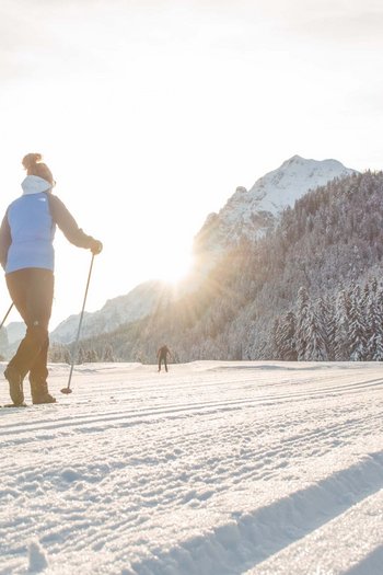 Hotel am Kronplatz direkt an der Piste Person beim Langlaufen auf verschneiter Berglandschaft im Sonnenlicht
