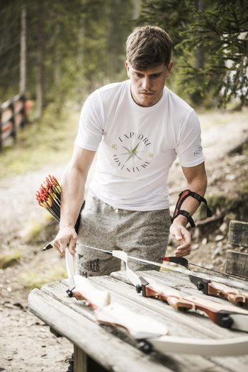 Excelsior: hotel wellness in Alto Adige per famiglie Uomo prepara arco e frecce per il tiro con l'arco nel bosco