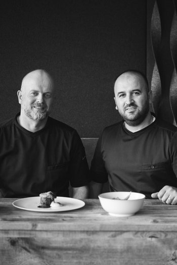 Your hotel in St. Vigil in Enneberg!! Two chefs sitting at a table with plates and a loaf of bread