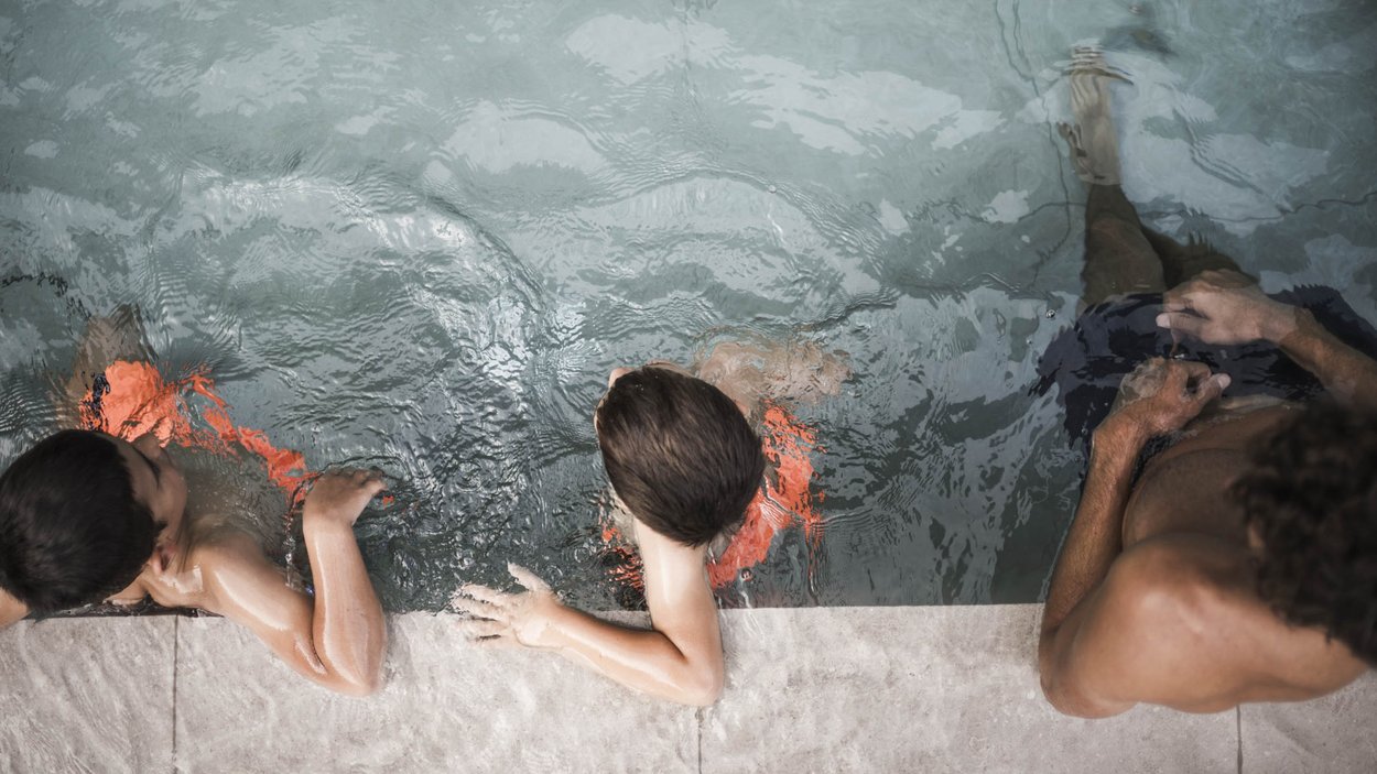 Family-friendly hotel in South Tyrol Two children and an adult at the edge of a swimming pool