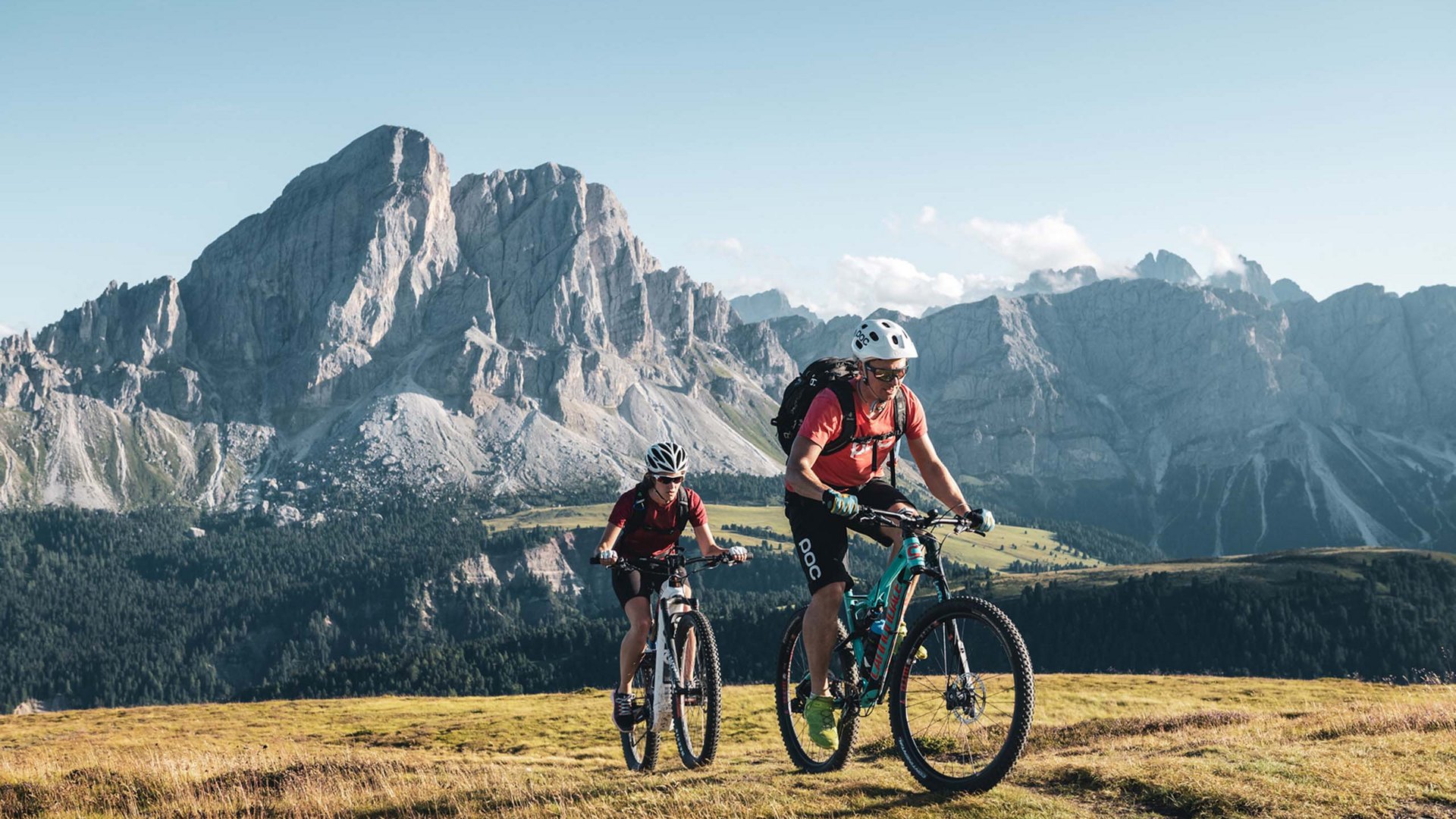Bike rental Two mountain bikers riding on a mountain trail with Alps in the background