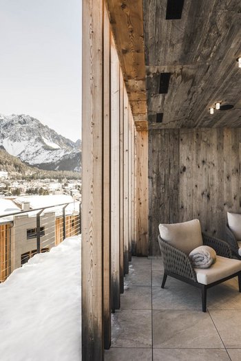 More than a hotel: Excelsior Cozy terrace with wooden ceiling and snowy mountain view over village