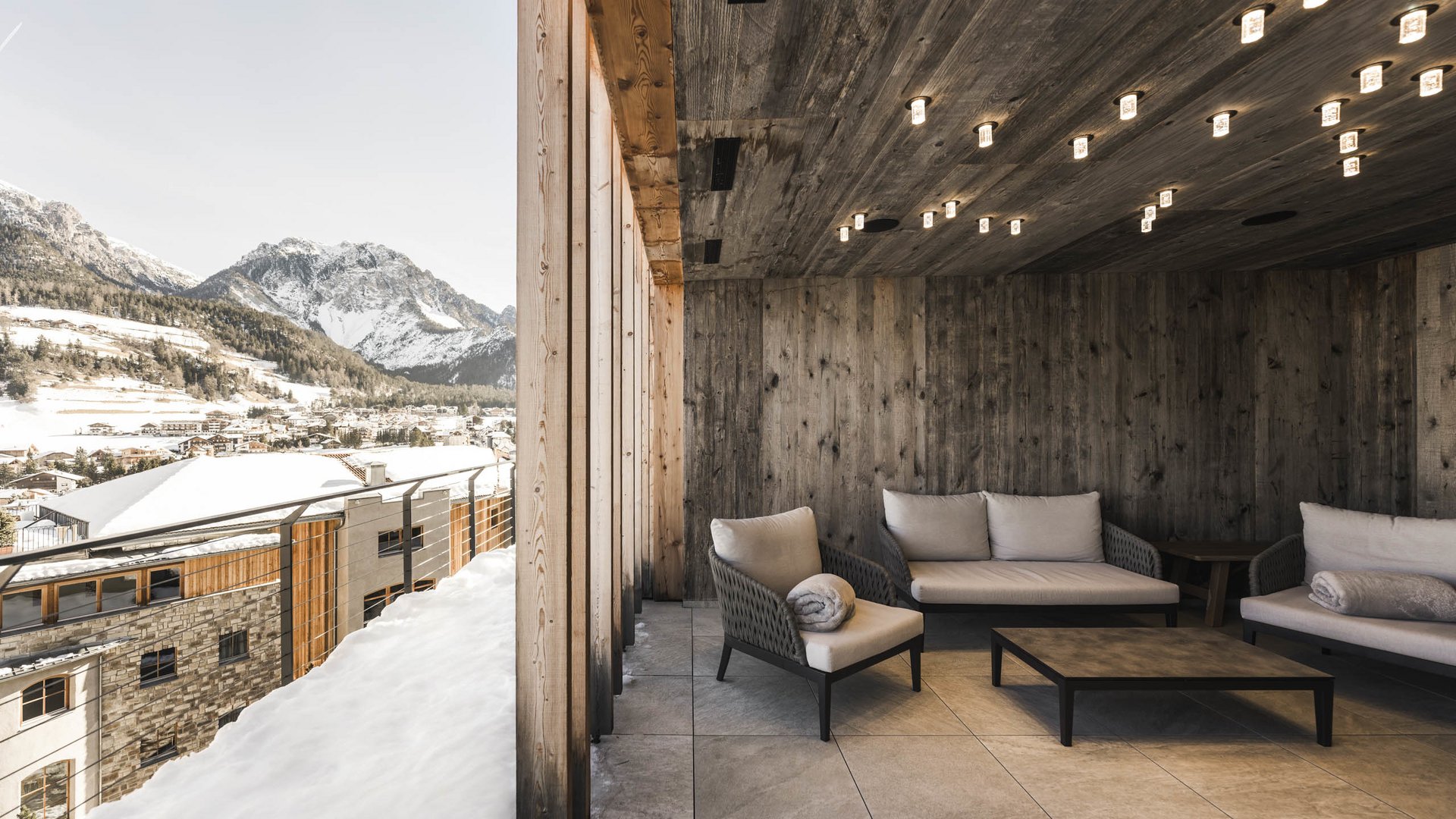 Belvita Leading Wellnesshotels Südtirol Gemütliche Terrasse mit Holzdecke und Bergblick im verschneiten Dorf