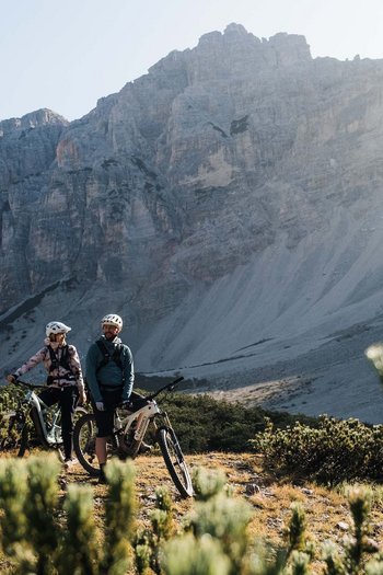 Bike offers and impressions Three mountain bikers with helmets in sunlit mountain landscape