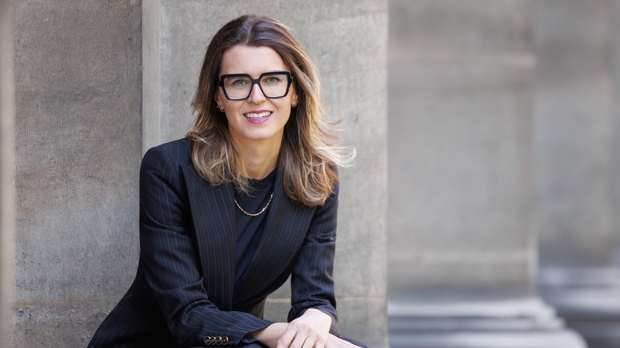 Dolomites hotel for mountain people Woman in black suit and glasses sitting by a building facade