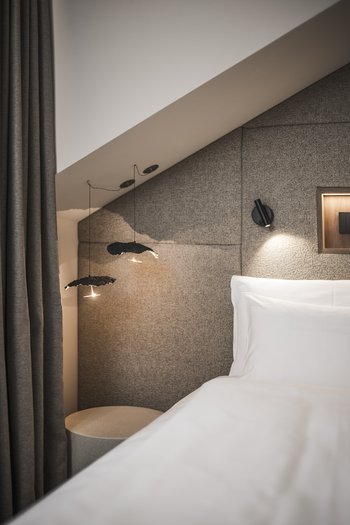 More than a hotel: Excelsior Modern bedroom with fabric wall, pendant lights, and bed with white bedding