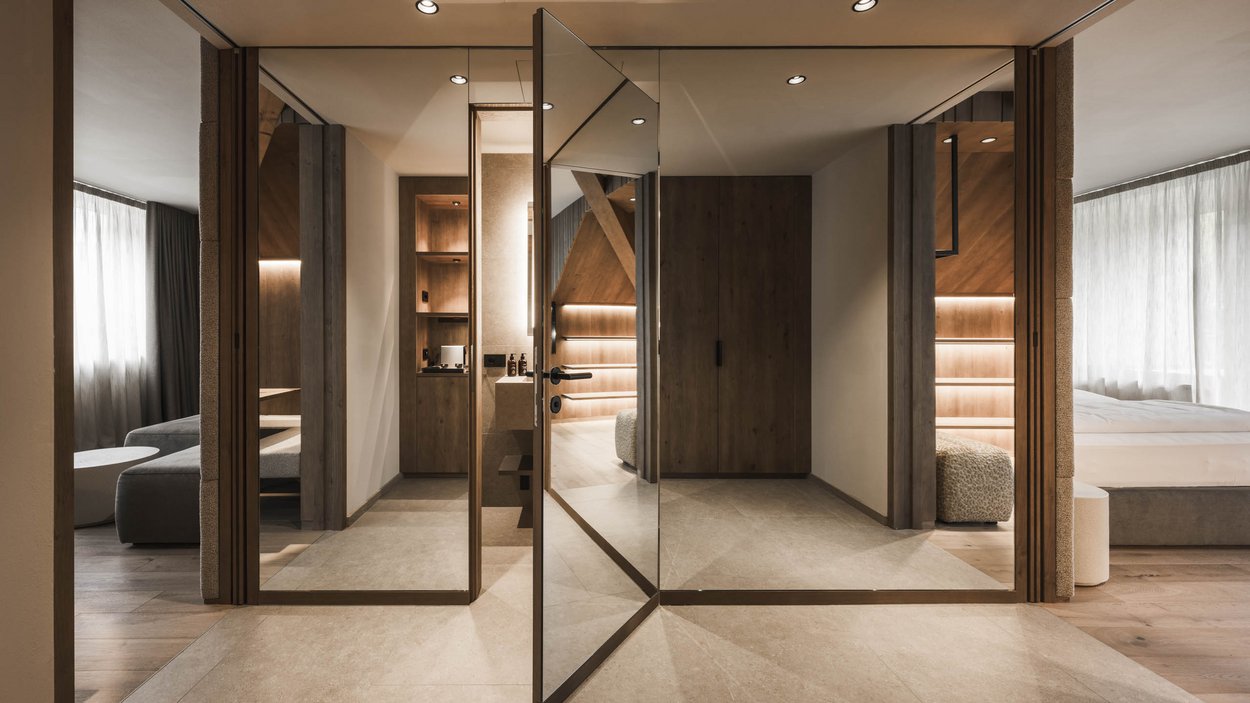 Family-friendly hotel in South Tyrol Modern hotel room hallway with mirrored revolving door and warm lighting