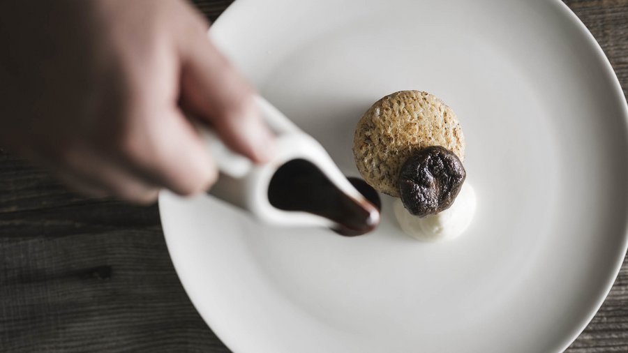 Hotel per celiaci Mano versa salsa scura su un piatto gourmet su piatto bianco