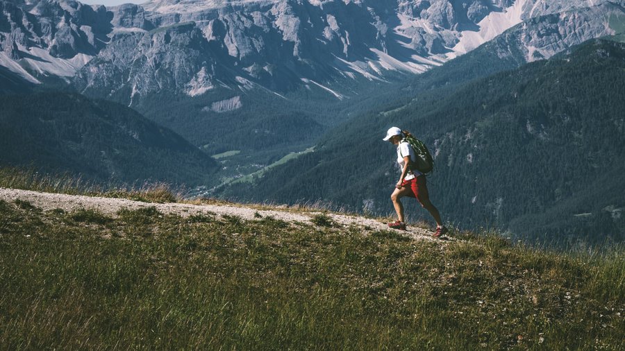 Kronplatz, Südtirol – Aktivitäten & Highlights Wanderer mit Rucksack auf Pfad vor Bergkulisse bei klarem Himmel