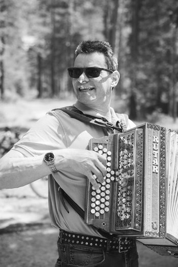 Your hotel in St. Vigil in Enneberg!! Man playing accordion outdoors with bicycles in the background