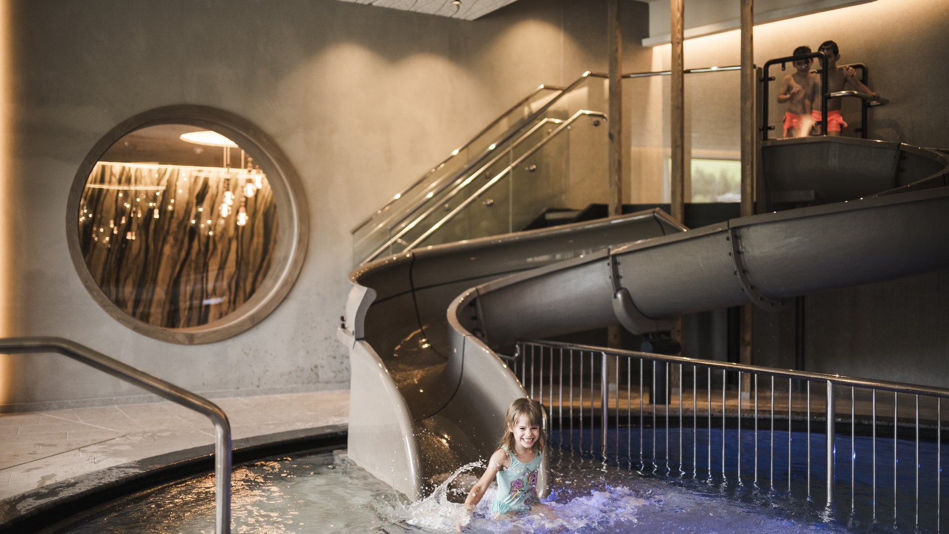 Excelsior: hotel wellness in Alto Adige per famiglie Bambina scende da scivolo d'acqua interno con altri bambini sopra