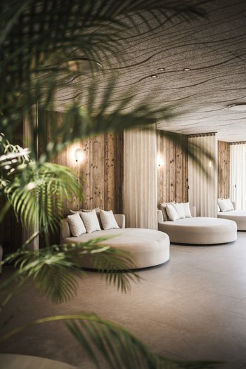 Family-friendly hotel in South Tyrol Modern lounge with round sofas, wooden walls, and green plants for cozy ambiance