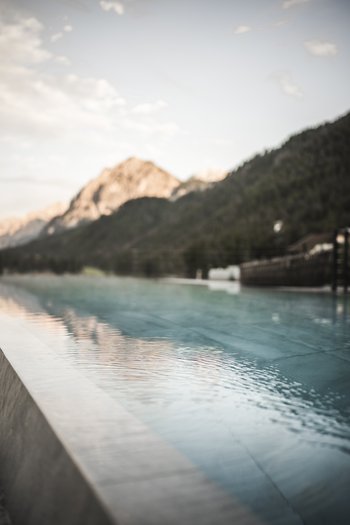 Hotel in the Dolomites for adults only Infinity pool with mountain view in soft morning light