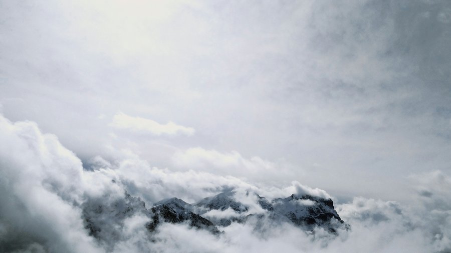Kronplatz, Südtirol – Aktivitäten & Highlights Verschneite Berggipfel umgeben von dichten Wolken unter grauem Himmel
