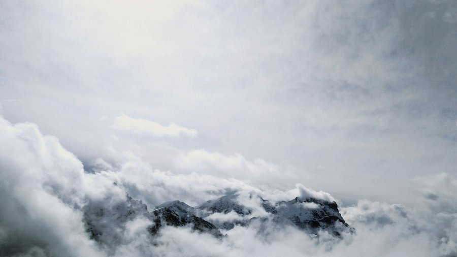 Plan de Corones, in Alto Adige: attività e highlight Cime innevate circondate da fitte nuvole sotto un cielo grigio