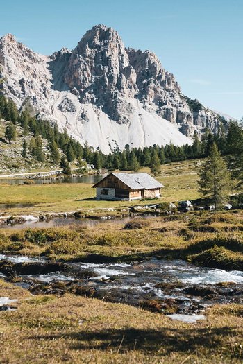 Il vostro sport hotel a San Vigilio di Marebbe Paesaggio montano con baita, fiume e pini in autunno soleggiato
