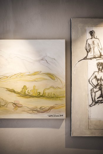 Kunst im Designhotel in Südtirol Zwei moderene Gemälde an einer Wand, eines mit Landschaft und eines mit Aktzeichnungen