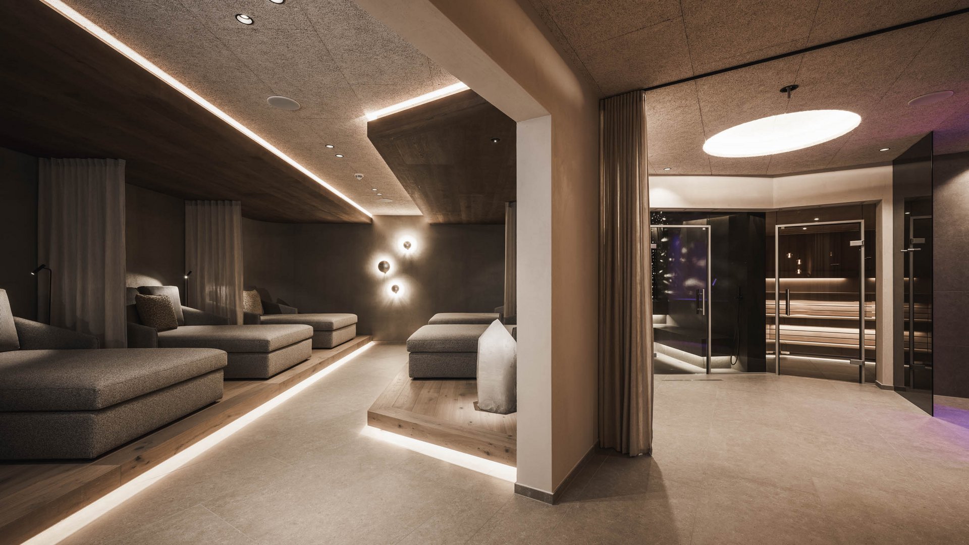 Wellnesshotel in den Dolomiten Moderner Wellnessbereich mit Ruheliegen und Sauna in warmem Licht