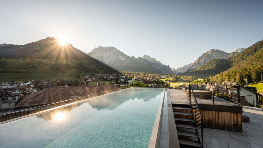 Excelsior: un hotel romantico in Alto Adige Piscina sul tetto con vista sulle montagne e alba su villaggio e valle