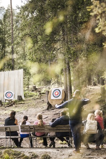 Hotel in South Tyrol with guided hikes Children and adults practicing archery in the forest in front of two targets