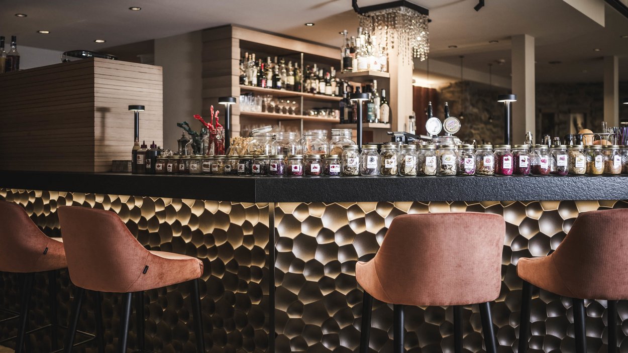 Il vostro hotel gourmet in Alto Adige Bar moderna con sgabelli rossi alti e barattoli di vetro sul bancone