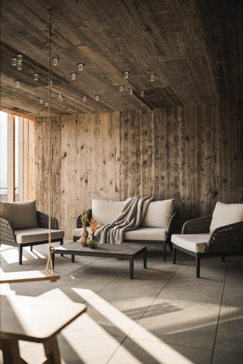 Wellnesshotel in Südtirol: Auf in den Traumurlaub! Gemütlicher Wohnbereich mit Sofa, Sesseln, Tisch und Holzverkleidung