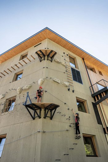 Excelsior: hotel wellness in Alto Adige per famiglie Bambini che arrampicano su una parete da arrampicata di un edificio moderno sotto il sole