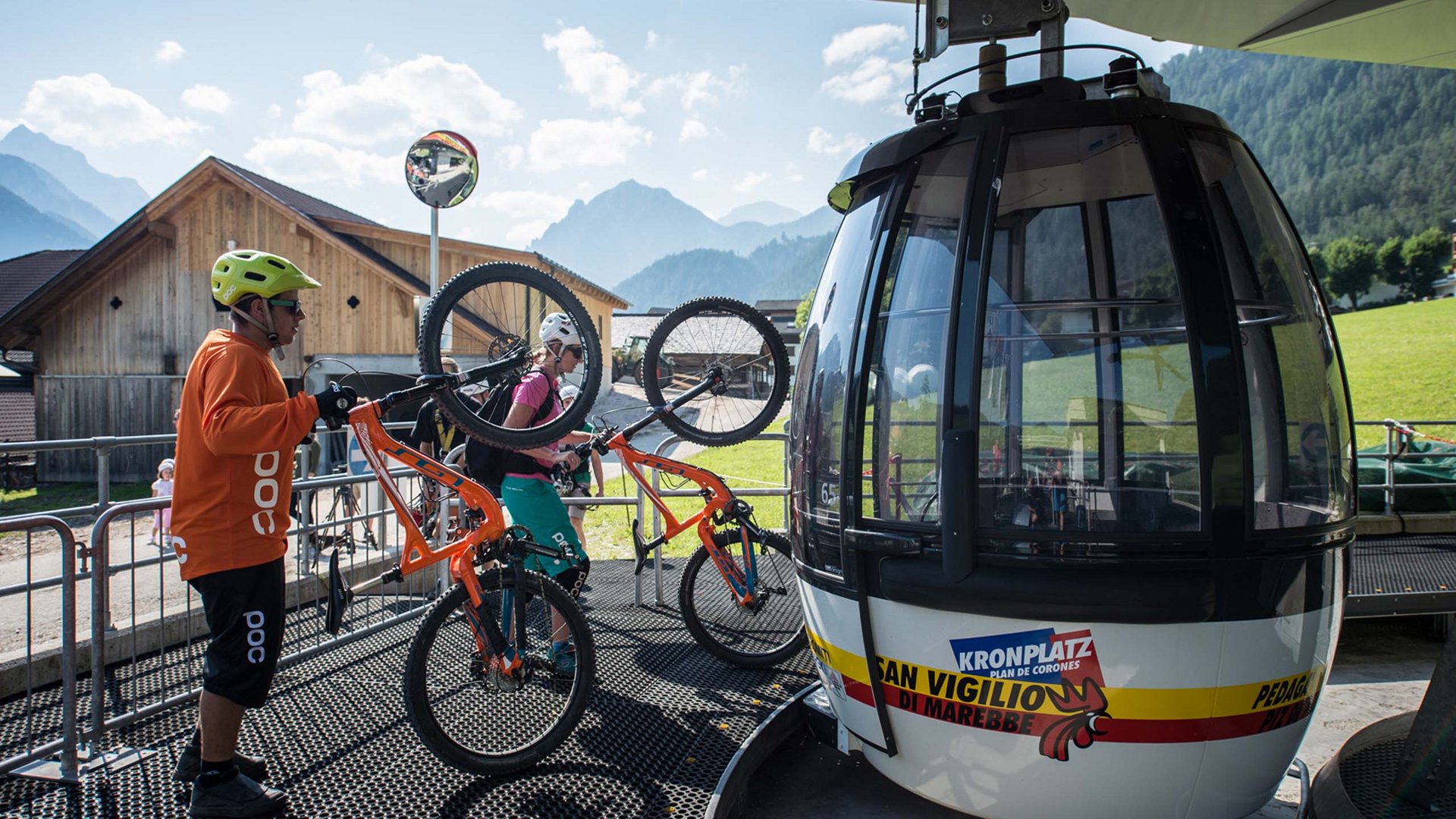 Bike-Verleih Zwei Radfahrer tragen ihre Mountainbikes zur Bergbahn in den Alpen