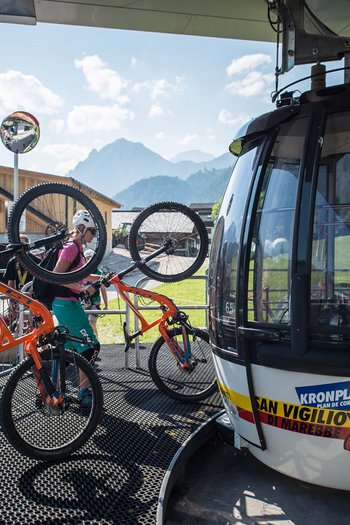Bike offers and impressions Two cyclists carrying mountain bikes to a cable car in the Alps