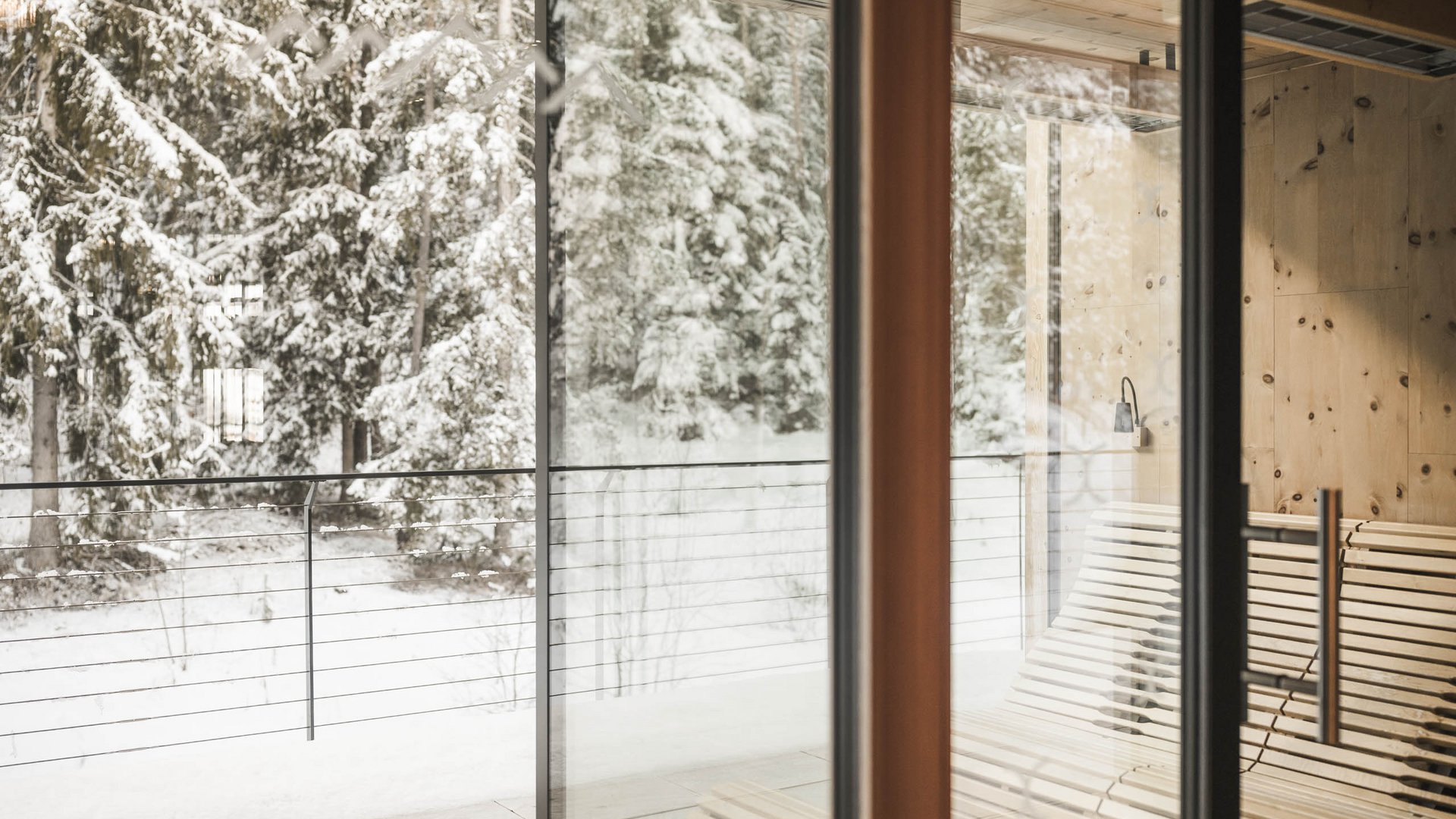 Hotel adults only in Alto Adige: l’Excelsior! Ambiente luminoso con panche in legno e vista su abeti innevati attraverso ampie vetrate