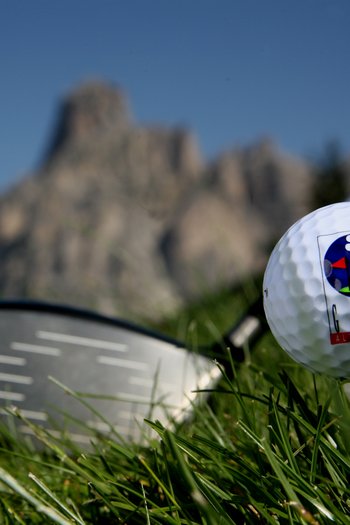 Il vostro sport hotel a San Vigilio di Marebbe Pallina da golf su tee con mazza e montagne sullo sfondo