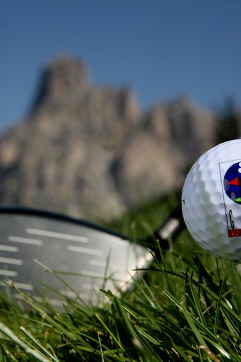 Il vostro sport hotel a San Vigilio di Marebbe Pallina da golf su tee con mazza e montagne sullo sfondo
